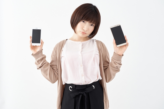 両手にスマートフォンを持つ女性