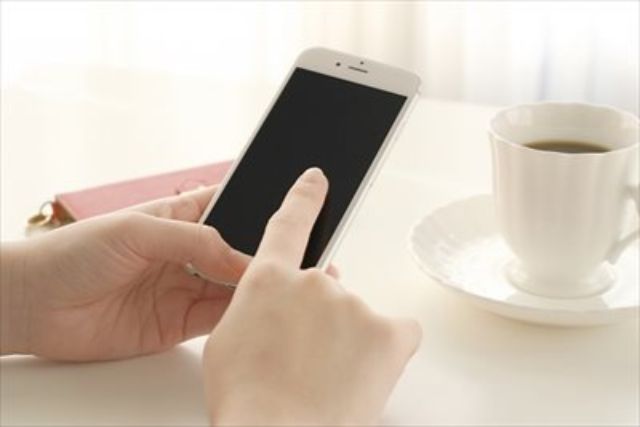 スマートフォンを操作する手とコーヒー