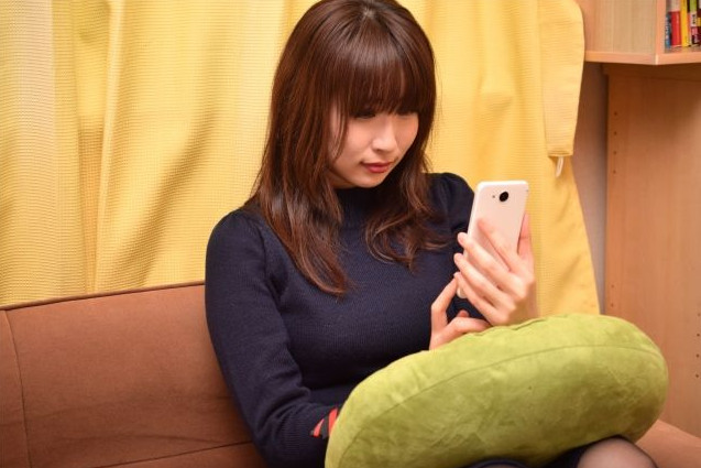ソファーでスマートフォンを触る女性